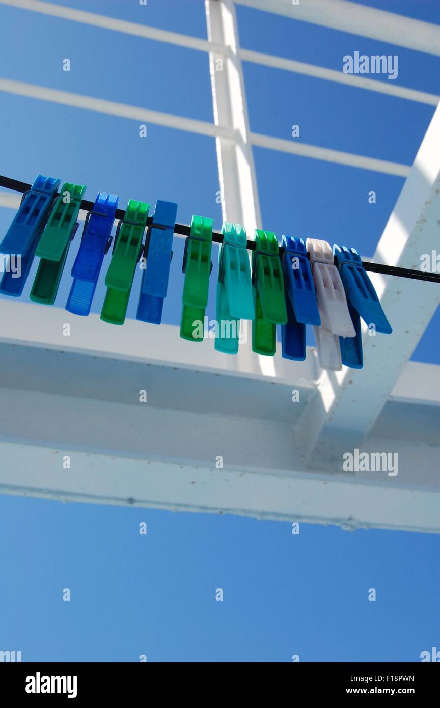 blue and green plastic pegs on a line on a Greek ferry against a blue sky Stock Photo