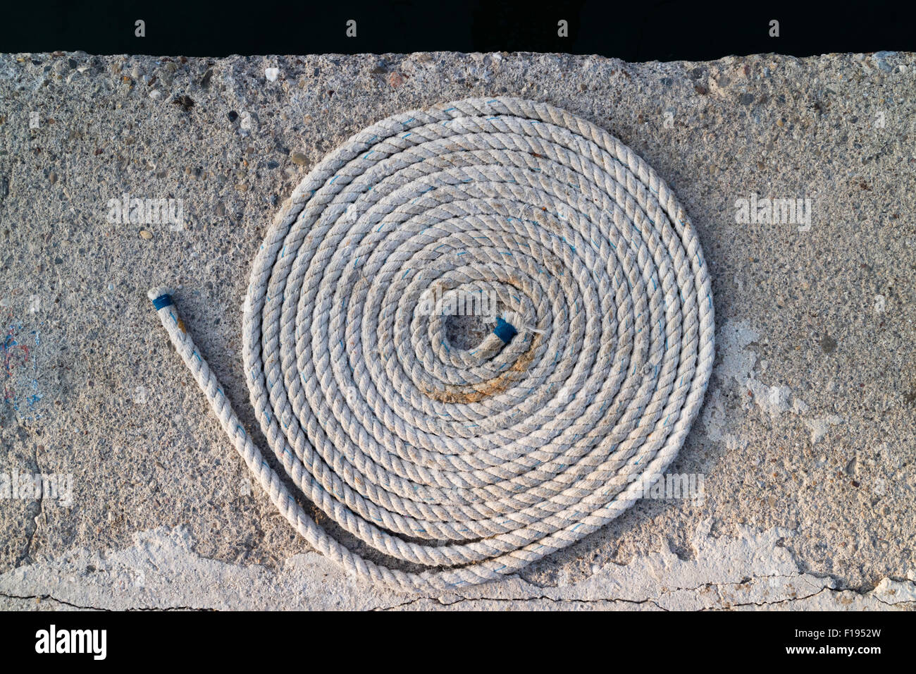 A neatly coiled rope lies on the ground Stock Photo