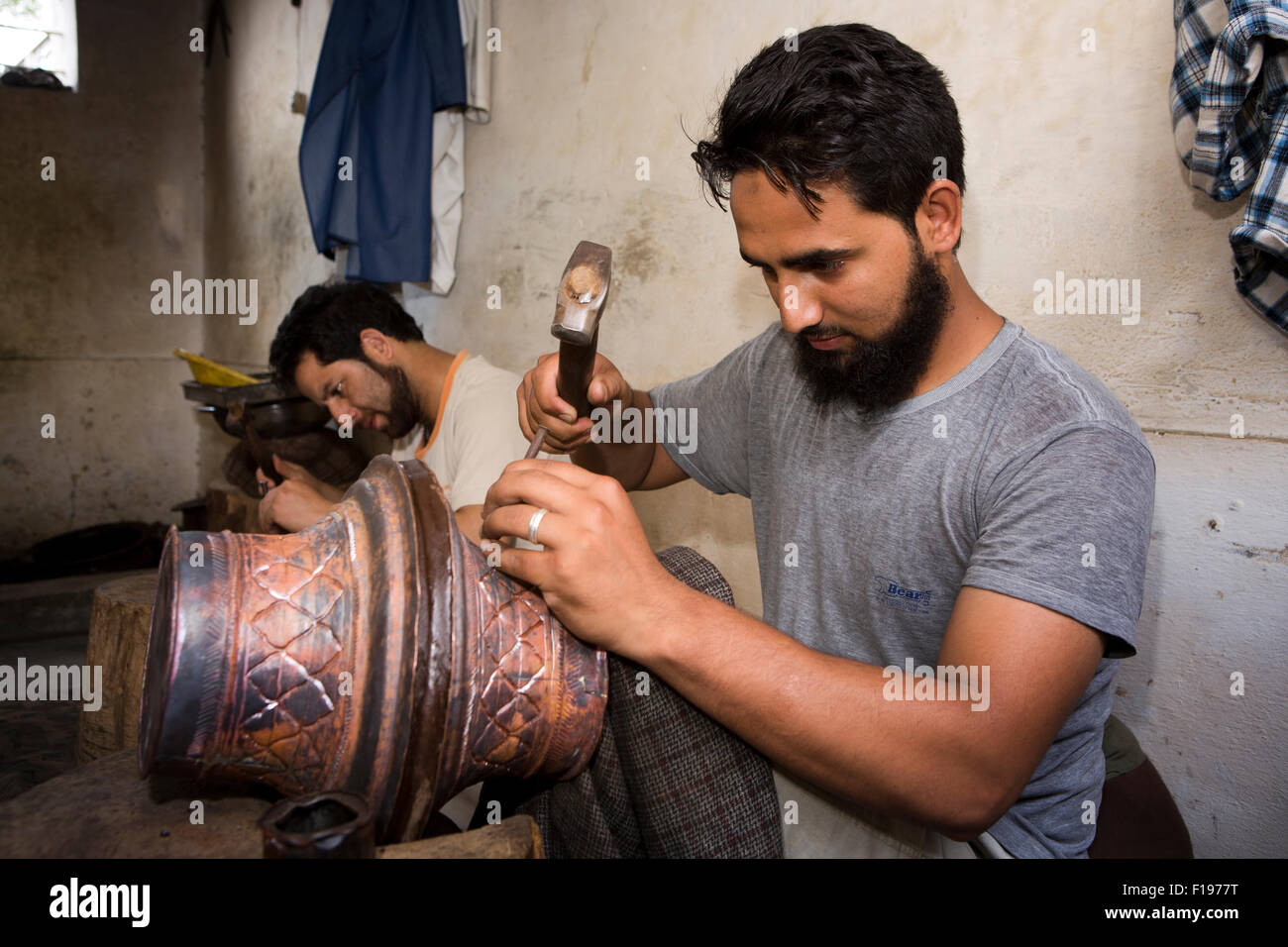 India, Jammu & Kashmir, Srinagar, Old City, crafts, craftsman punching pattern onto copper pot Stock Photo