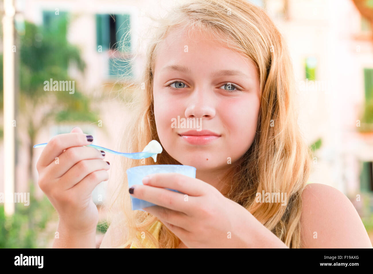 Blond Caucasian teenage girl eats frozen yogurt, close up outdoor portrait with natural light Stock Photo