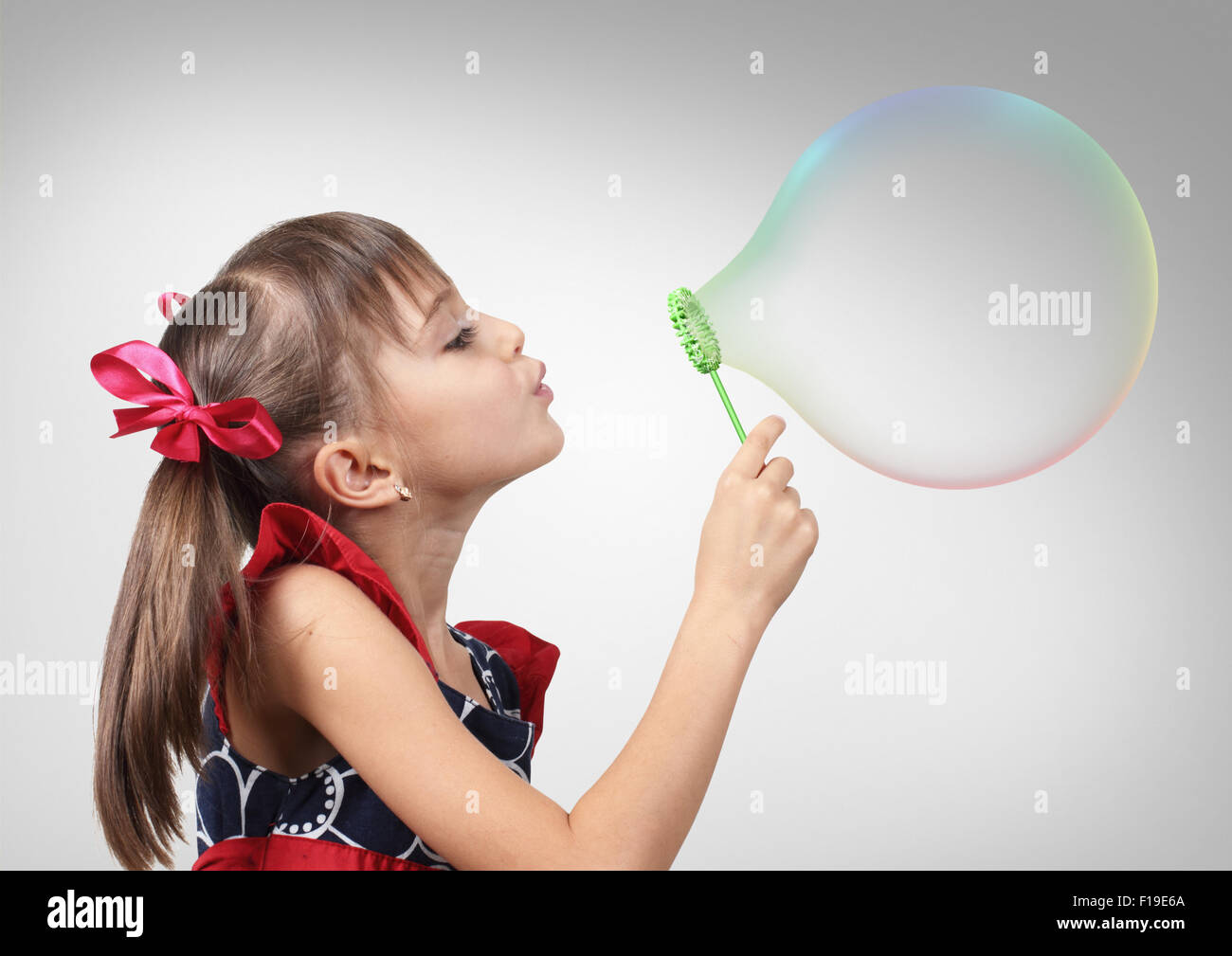 Portrait of child girl blowing big soap bubble, studio shot Stock Photo