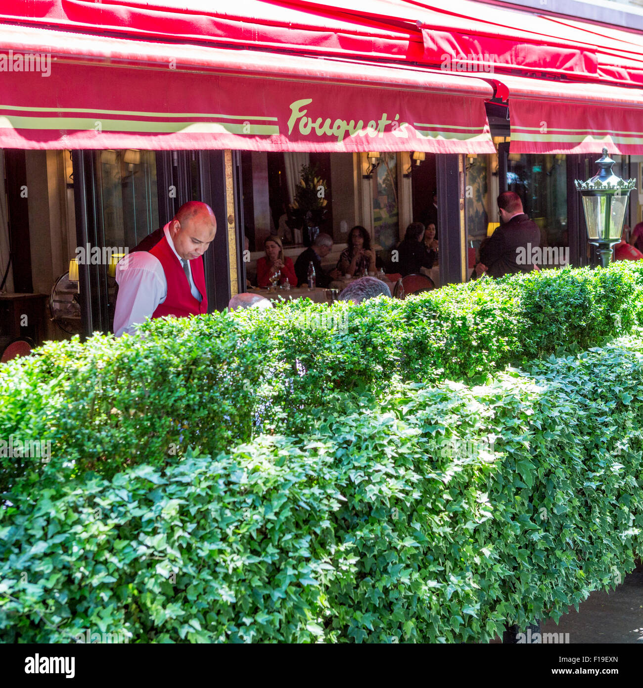 Waiter serves patrons at famed Restaurant Le Fouquet's on the Avenue des Champs Elysees in Paris Stock Photo