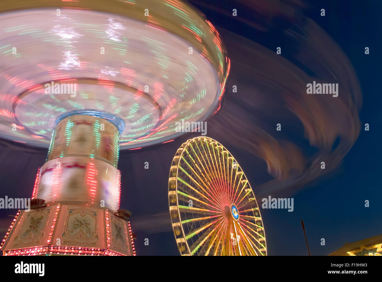 Funfair with giant wheel and merry go round in motion evening light germany europe Stock Photo