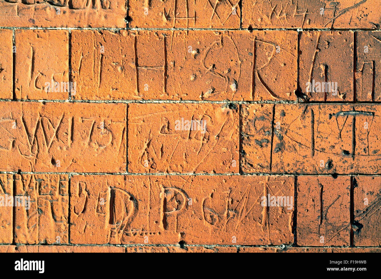 Brick Wall with carved signs and words Stock Photo