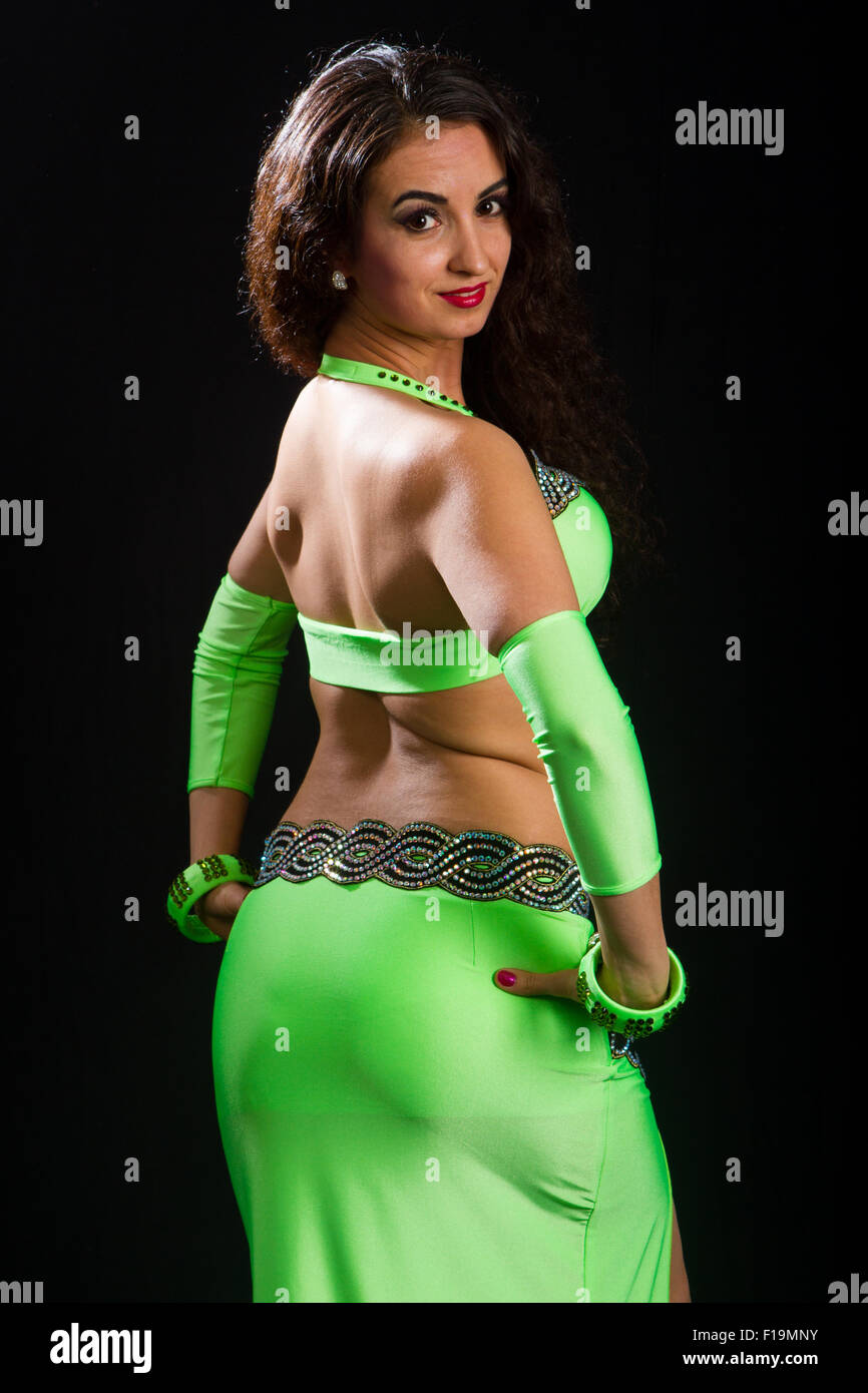 beautiful young brunette in a green suit oriental dance on black background Stock Photo