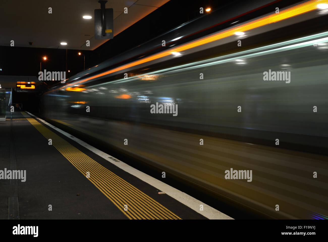 Time exposure as a commuter train leaves a suburban train station in the evening Stock Photo