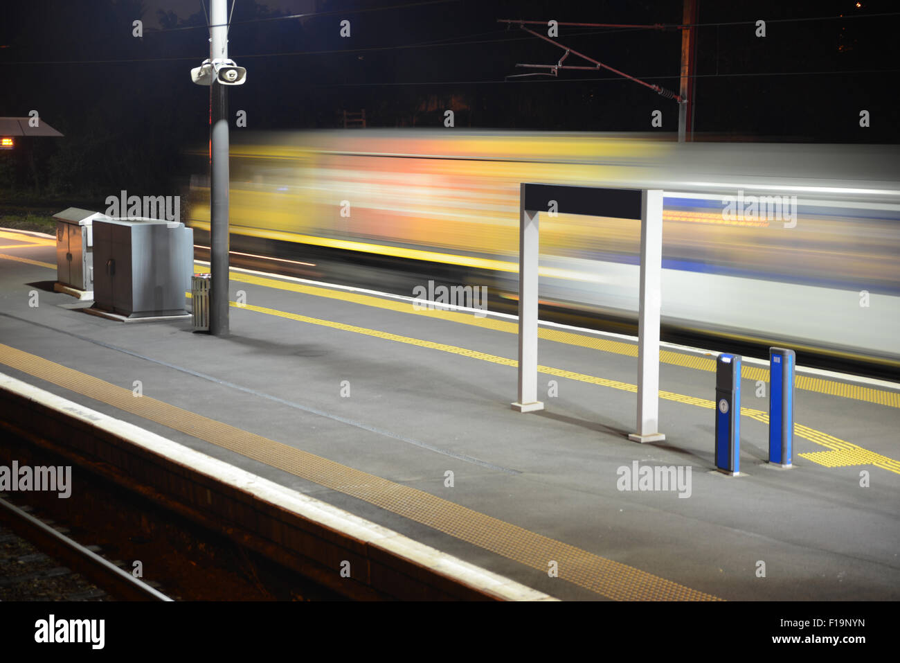 Time exposure as a commuter train leaves a suburban train station in the evening Stock Photo