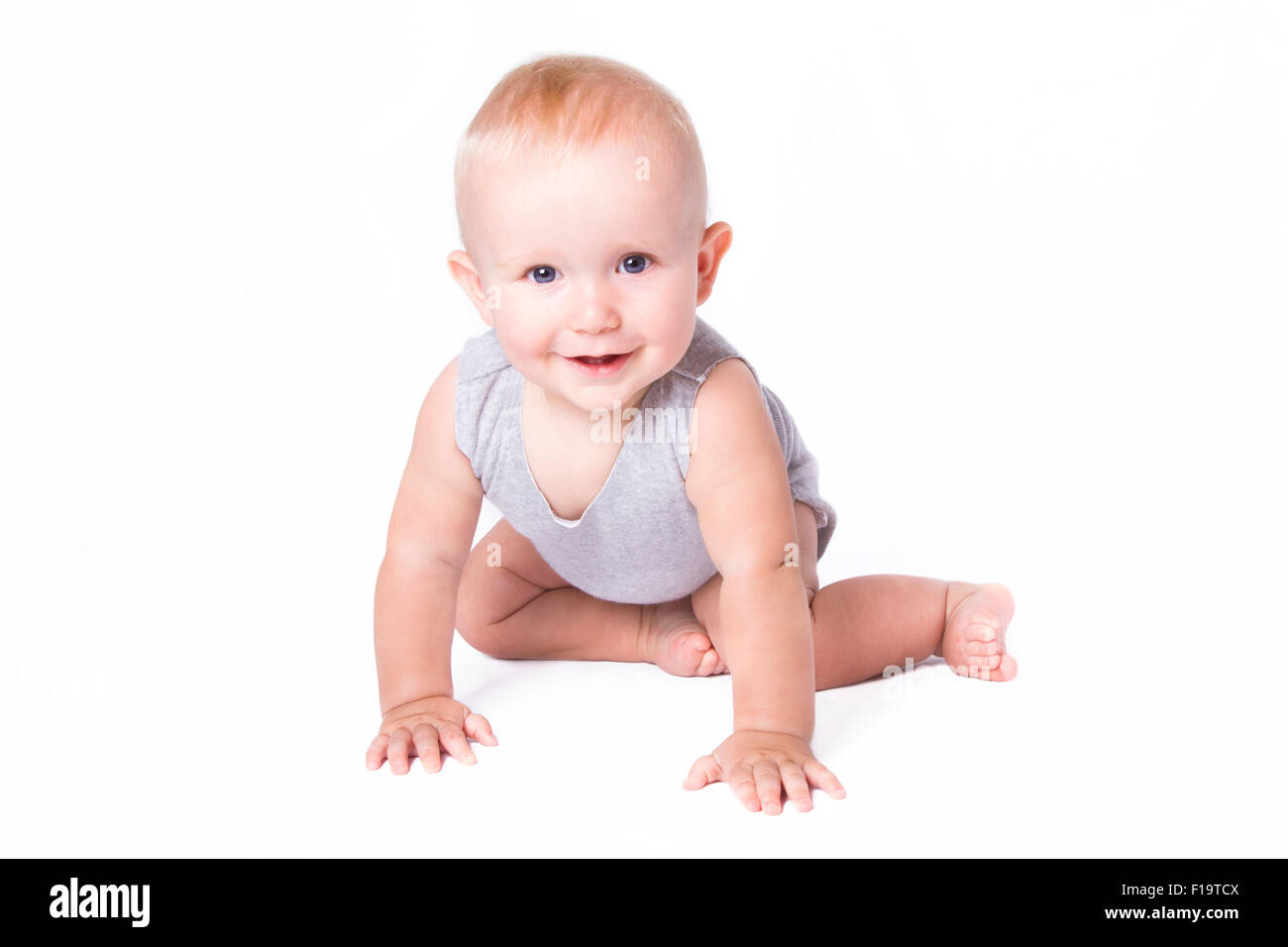 Studio shot of baby boy playing on the floor looking at the camera. Stock Photo