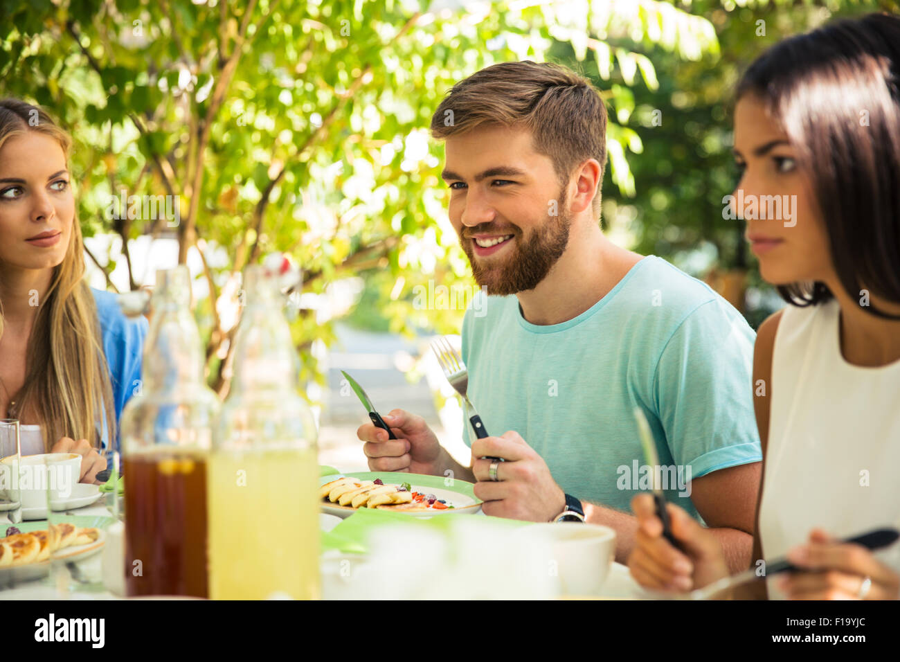Group of a smiling friends sitting in outdoor restaurant Stock Photo