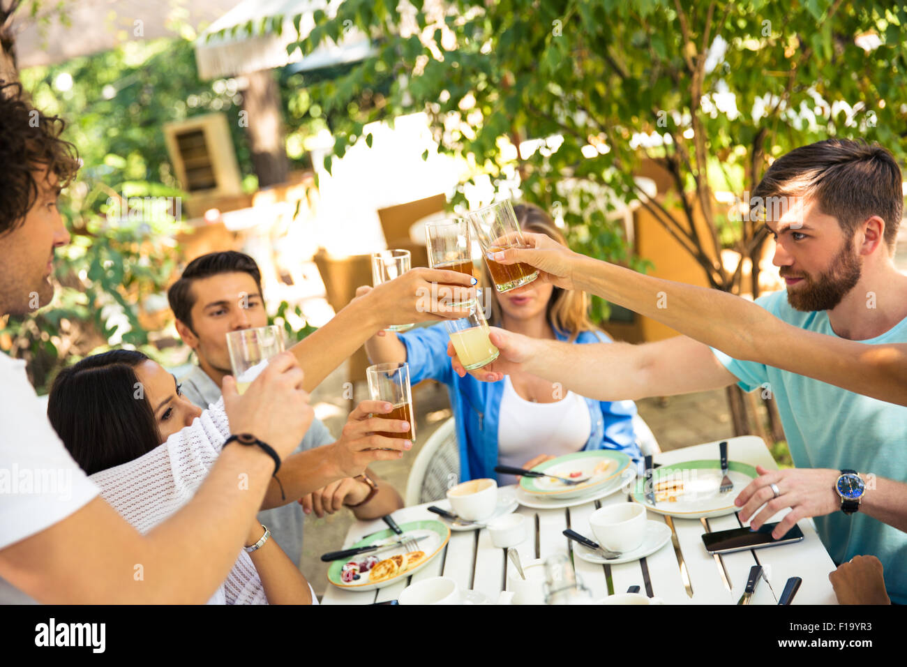 Group of a friends making toast around table at dinner party in outdoor restaurant Stock Photo