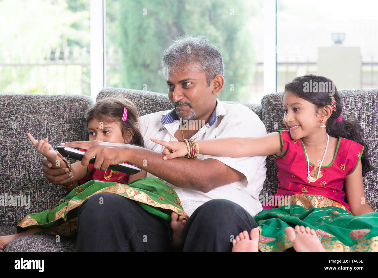 Happy Indian family watching tv together, switching channel with remote ...