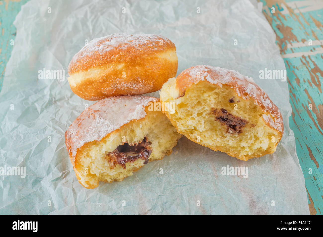Sweet sugary donuts filled with chocolate cream on rustic wooden kitchen table, tasty bakery doughnuts, selective focus Stock Photo