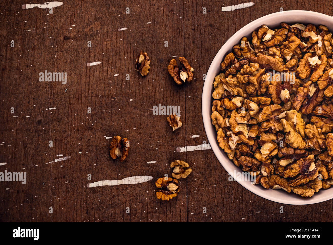 Peeled Walnut Kernels in Ceramic Bowl on Brown Rustic Wood Plank Background, Top View Stock Photo