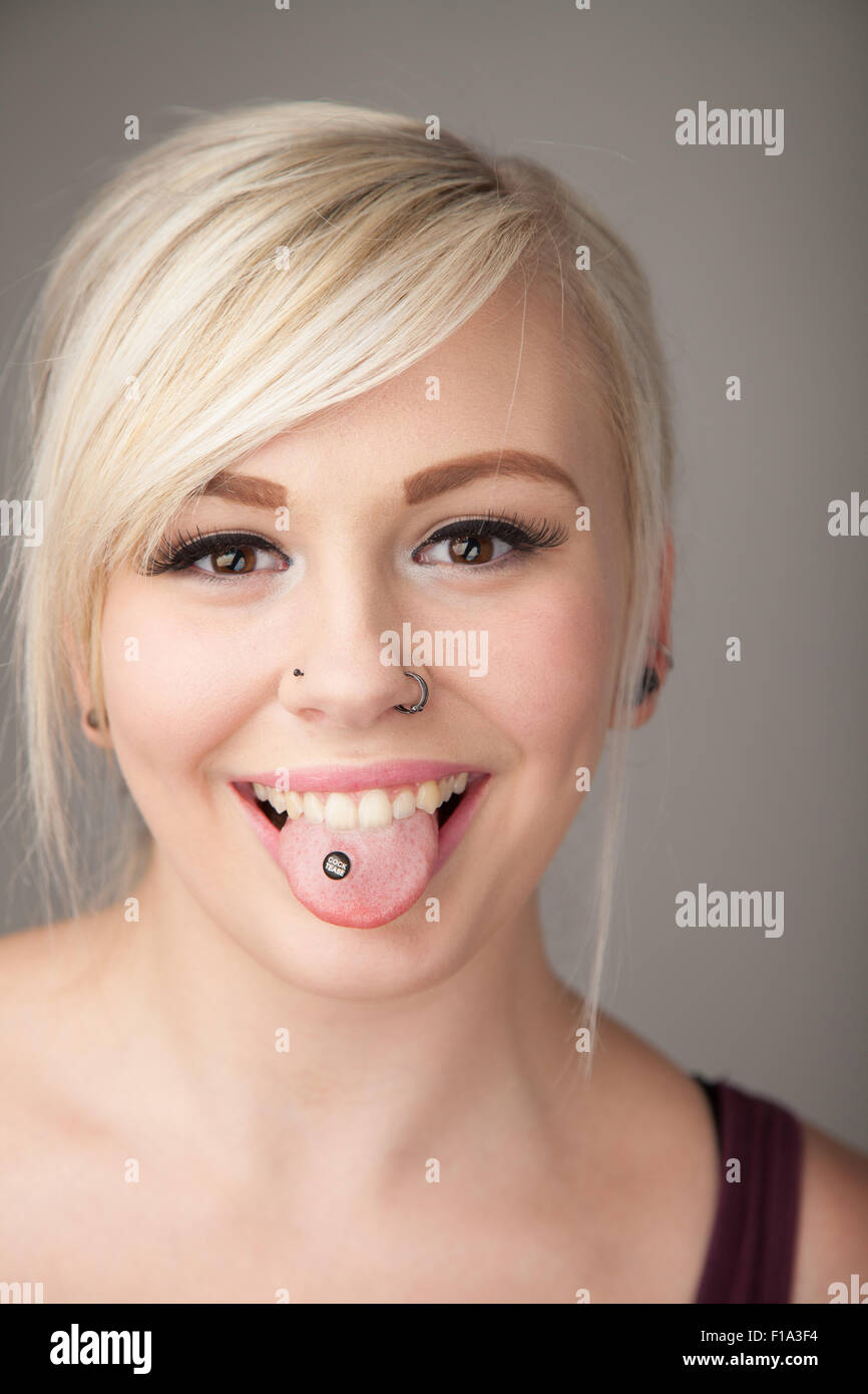 Cute looking teenage girl with her pierced tongue sticking out. Stock Photo