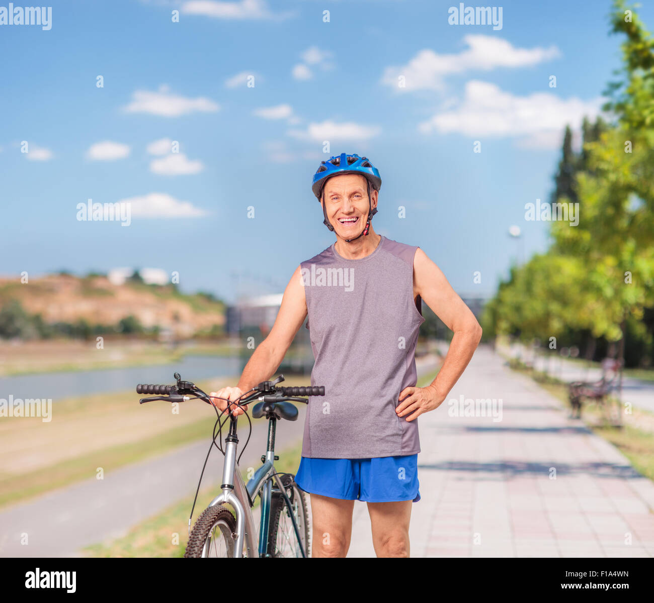 Active senior man posing with his bicycle and standing on a sidewalk outdoors shot with tilt and shift lens Stock Photo