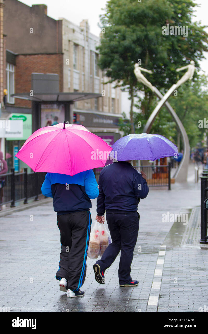 Northampton, U.K. 31st Aug 2015. People under colourful umbrellas in the town centre on a this wet August Bank holiday Monday in Abington street, Northampton, nearly midday and there's still heavy rain falling latest forecast is that it will subside by mid afternoon. Credit:  Keith J Smith./Alamy Live News Stock Photo
