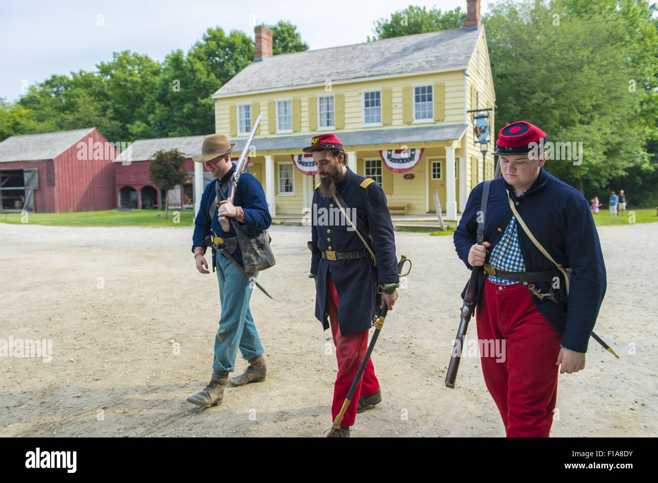 Old Bethpage, New York, USA. 30th Aug, 2015. At center, Andrew Preble from Long Beach portrays an American Civil War Captain from the 14th Brooklyn Regiment (14th New York State Militia) AKA The Brooklyn Chasseurs, in front of the yellow and white Noon Inn tavern during the Old Time Music Weekend at the Old Bethpage Village Restoration. During their historical reenactments, members of the non-profit 14th Brooklyn Company E wear accurate reproductions of ''The ''Red Legged Devils'' original Union army uniform. Credit:  Ann Parry/ZUMA Wire/Alamy Live News Stock Photo