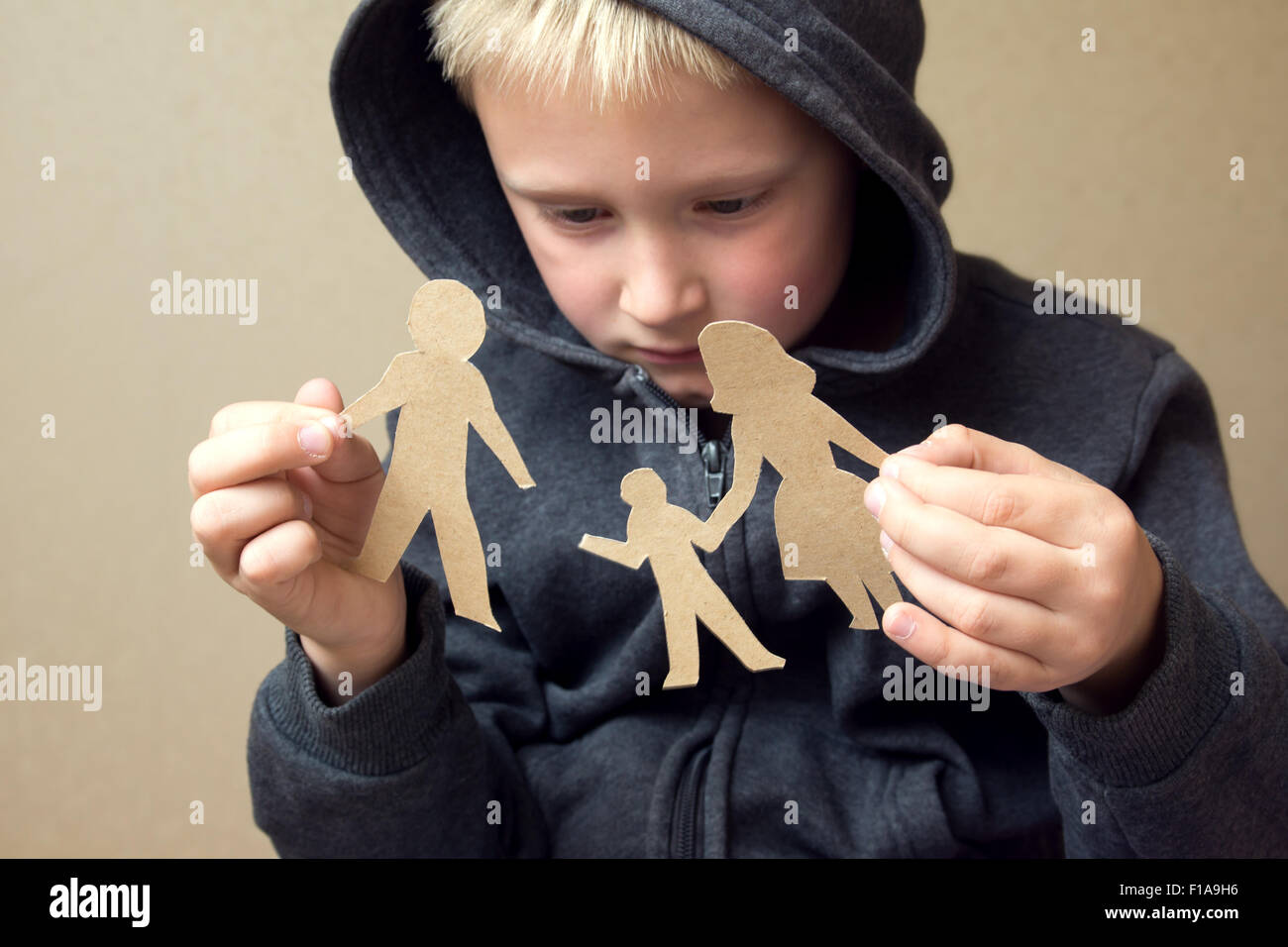 Confused child with broken paper family, family problems, divorce, custody battle, suffer concept Stock Photo