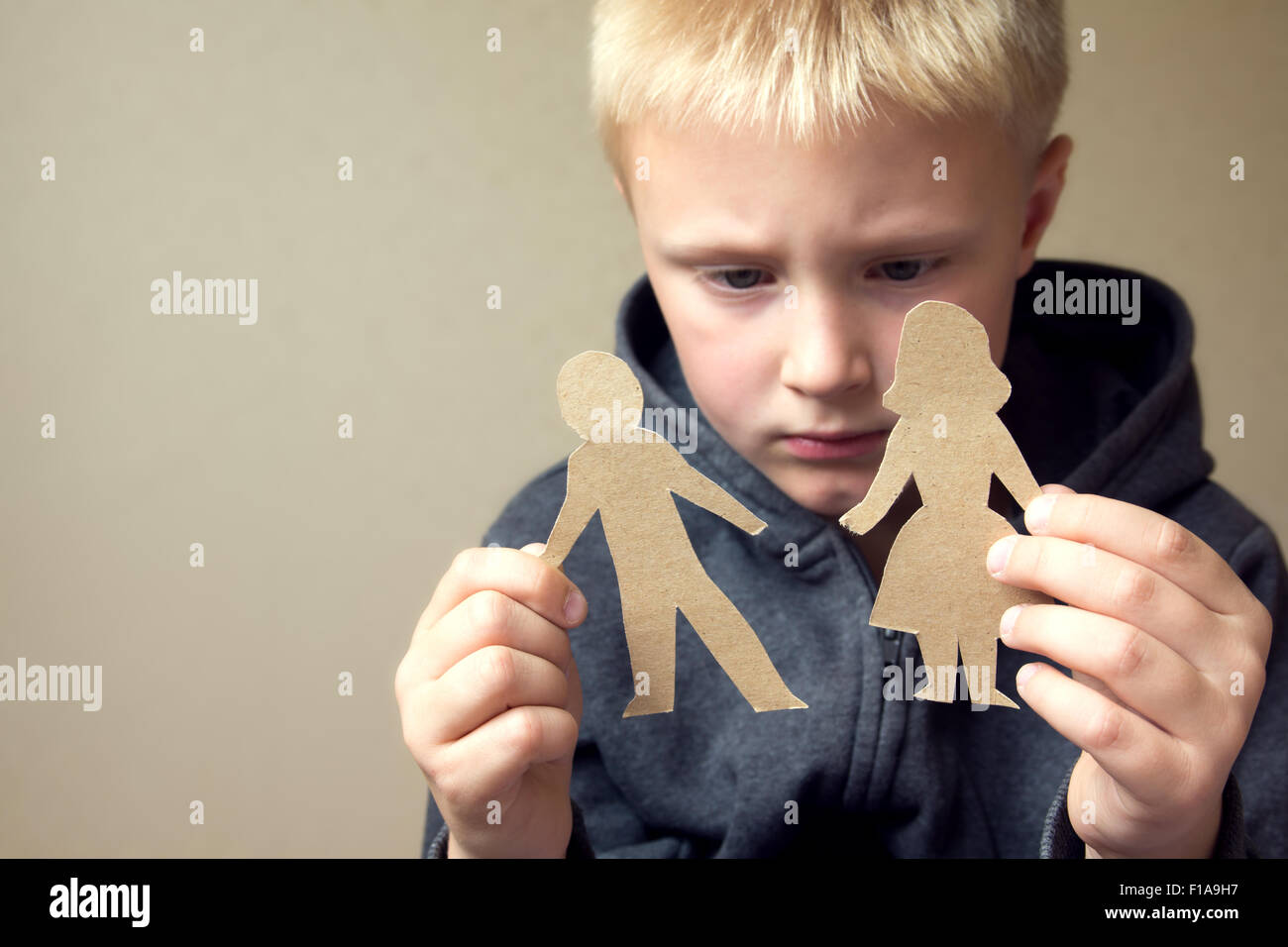 Confused child with cutting paper parents, family problems, divorce, custody battle, suffer concept Stock Photo