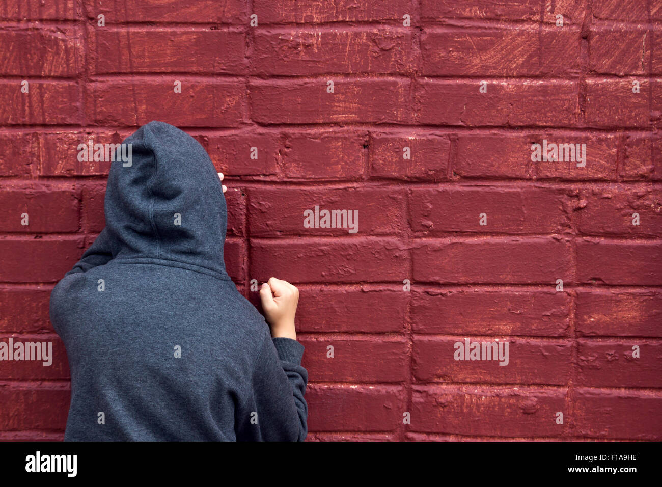 Worried depressed sad teen boy (child) crying near brick wall Stock Photo