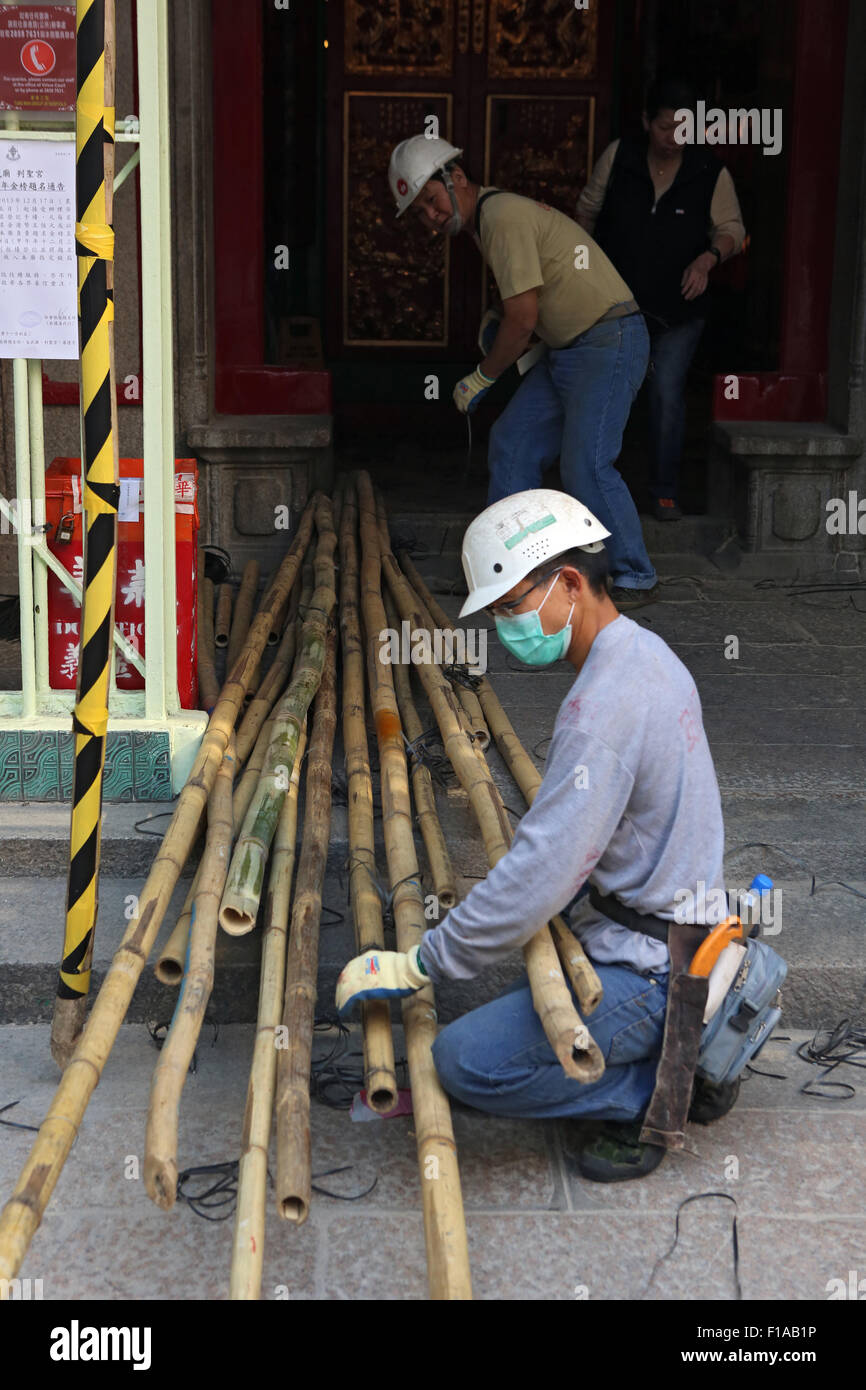 Hong Kong, China, construction worker kneels before long Bambusstaeben Stock Photo