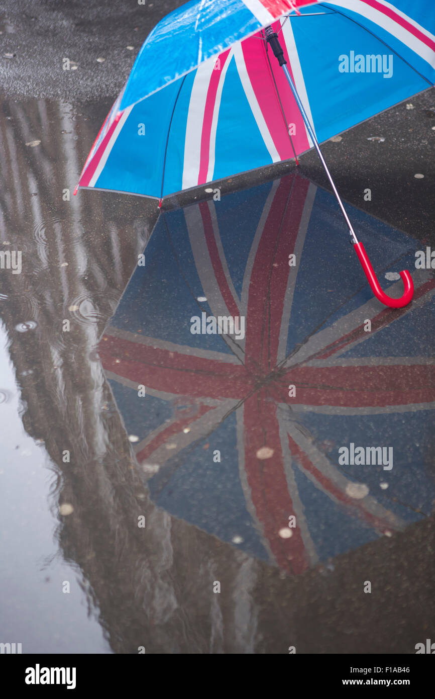 An umbrella showing the British flag (Union Jack) reflected on a rainsoaked pavement in London