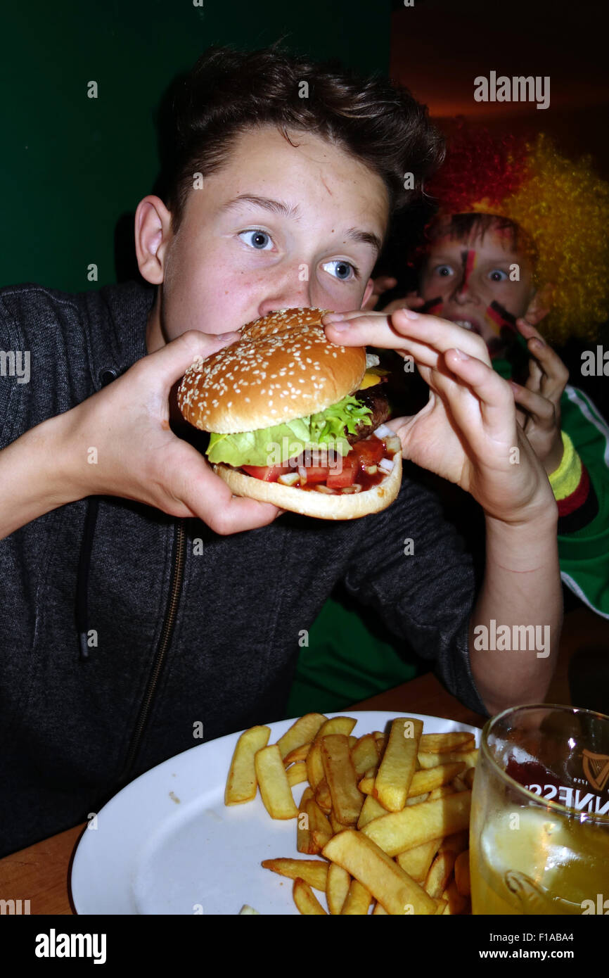Berlin, Germany, boy eating a burger with fries Stock Photo
