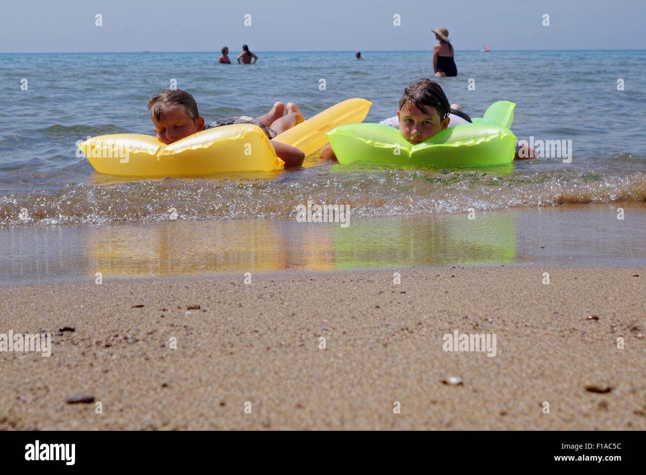 Populonia, Italy, two boys are bored on their air mattresses in the sea Stock Photo