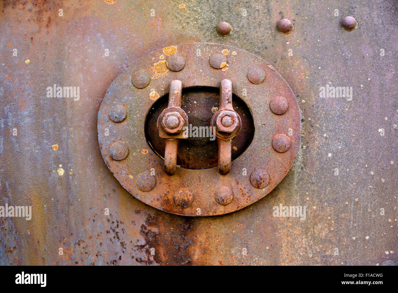 Backgrounds and textures: closed hatch on rusty metal surface with riveted joints, industrial abstract Stock Photo