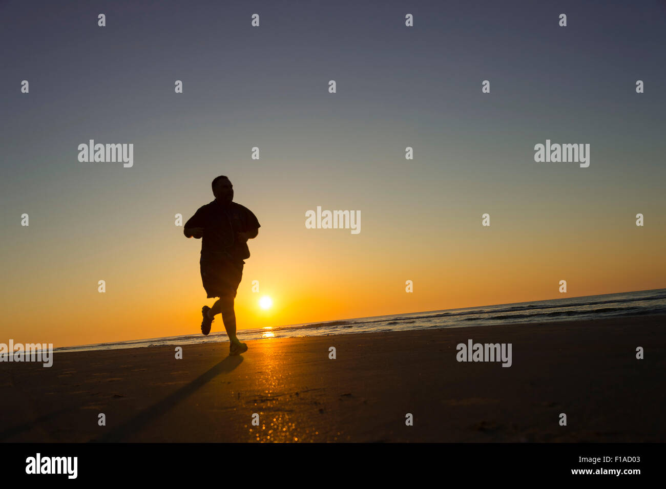 Over Weight Runner Running On Beach At Sunrise Stock Photo