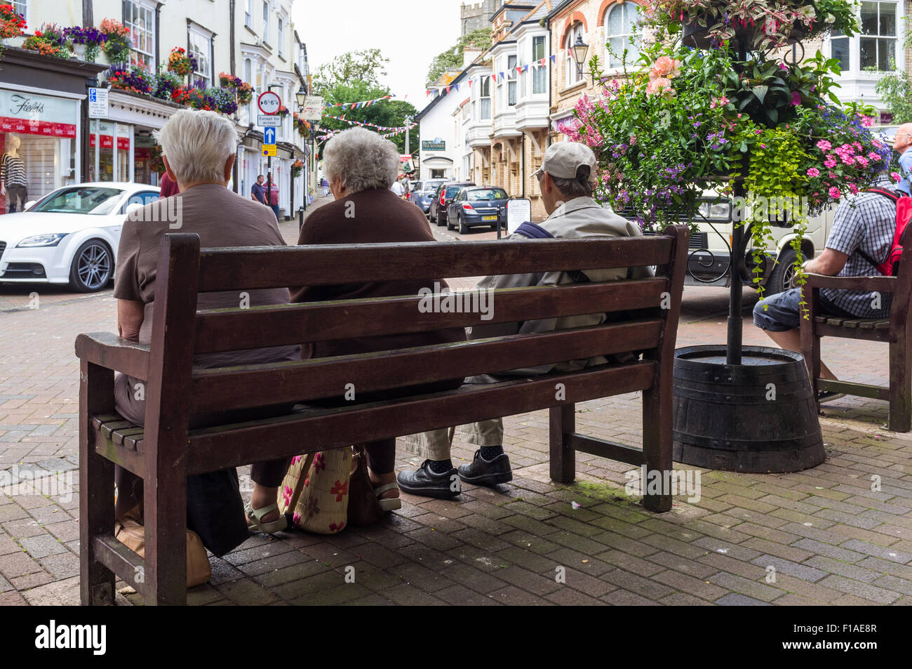 Sidmouth, Devon. 2015. A group of three pensioners are sitting on a public bench in Sidmouth town centre. Stock Photo