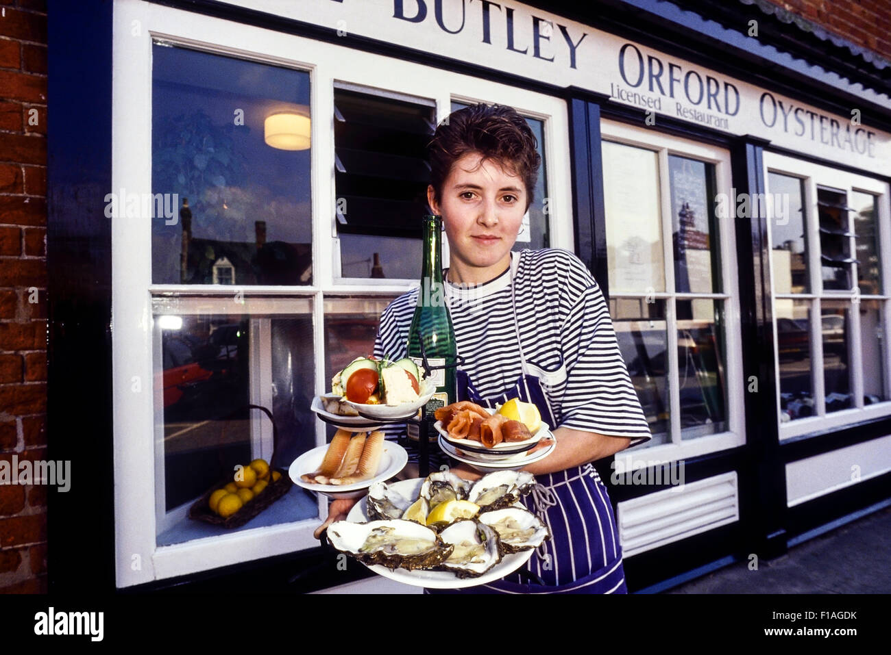 A waitress holding a selection of fresh oysters and smoked fish at The Butley Orford Oysterage. Suffolk. England. UK Stock Photo