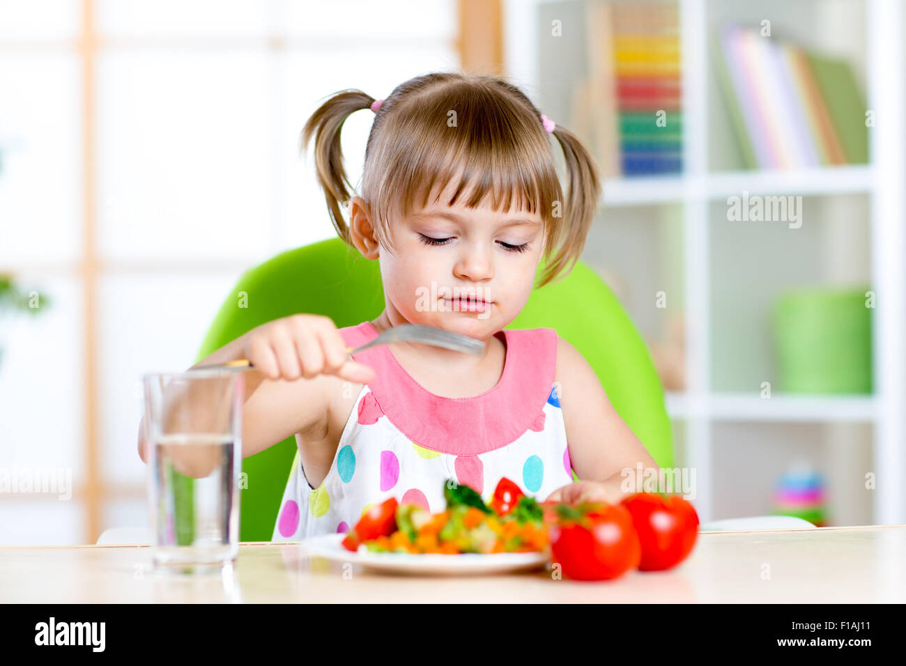 Kid girl eats fresh vegetables. Healthy eating for child Stock Photo