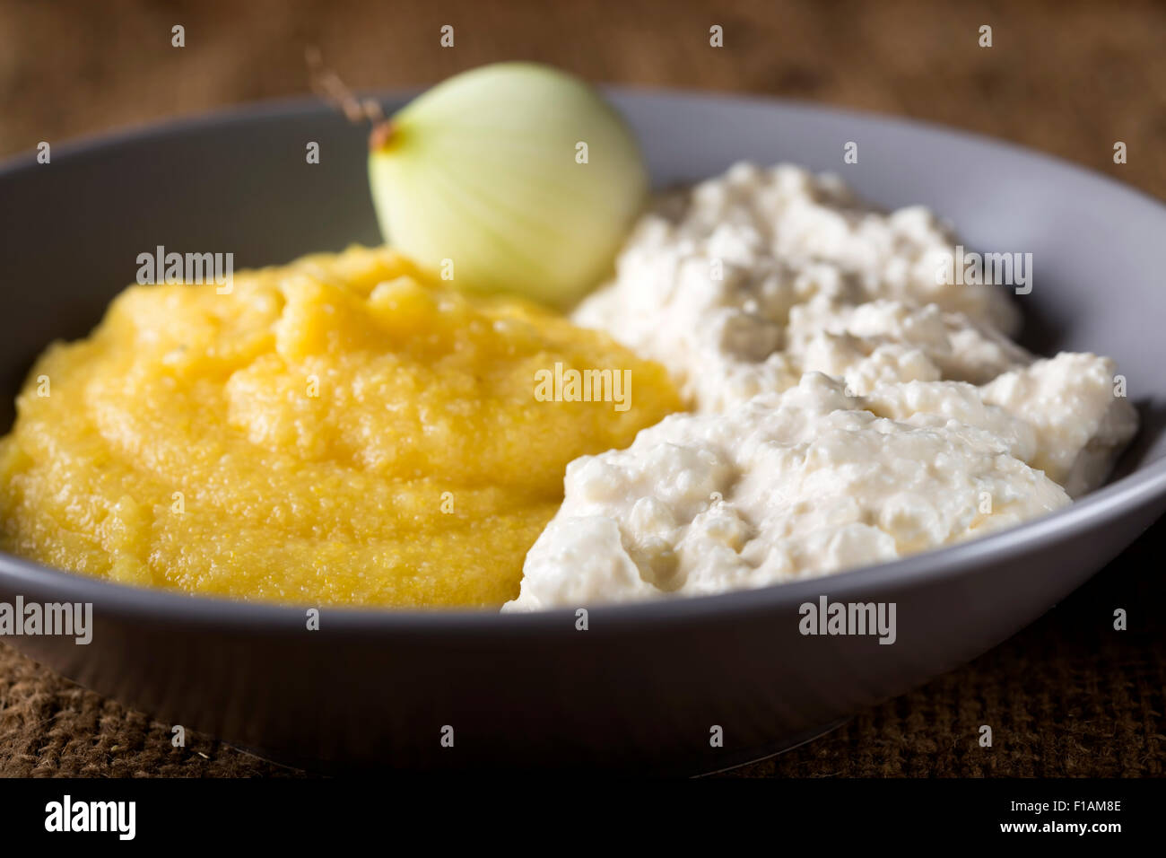 Polenta, cheese with cream and fresh onion on plate Stock Photo