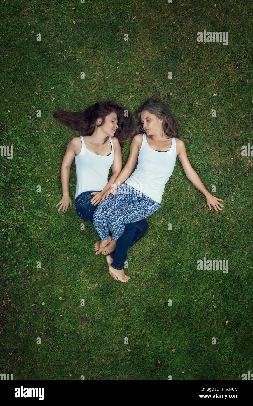 Two sisters lying on a meadow with closed eyes Stock Photo - Alamy