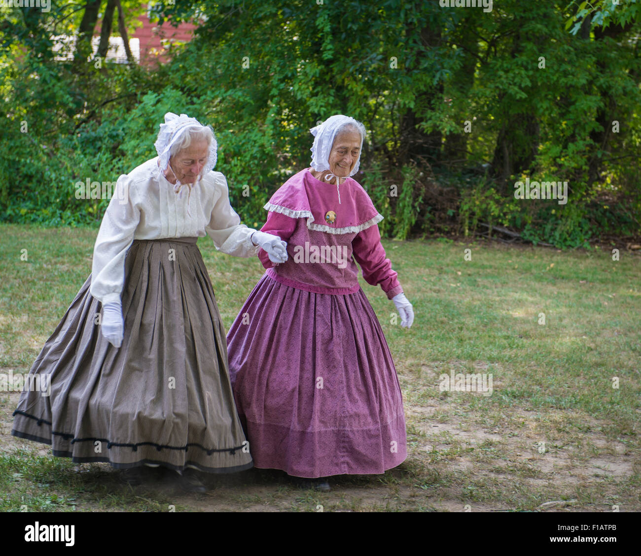 Old Bethpage, New York, USA. 30th August, 2015. L-R, identical twin sisters JULIETTE FOX of Hicksville, and PATRICIA JOSEPH of College Point, wearing Civil War era style long hoop skirt clothing, are member of the Old Bethpage Village Dancers which danced throughout the Old Time Music Weekend at Old Bethpage Village Restoration, where popular music of the American Civil War period was performed, and visitors learned traditional 1800's contradances. Credit:  Ann E Parry/Alamy Live News Stock Photo