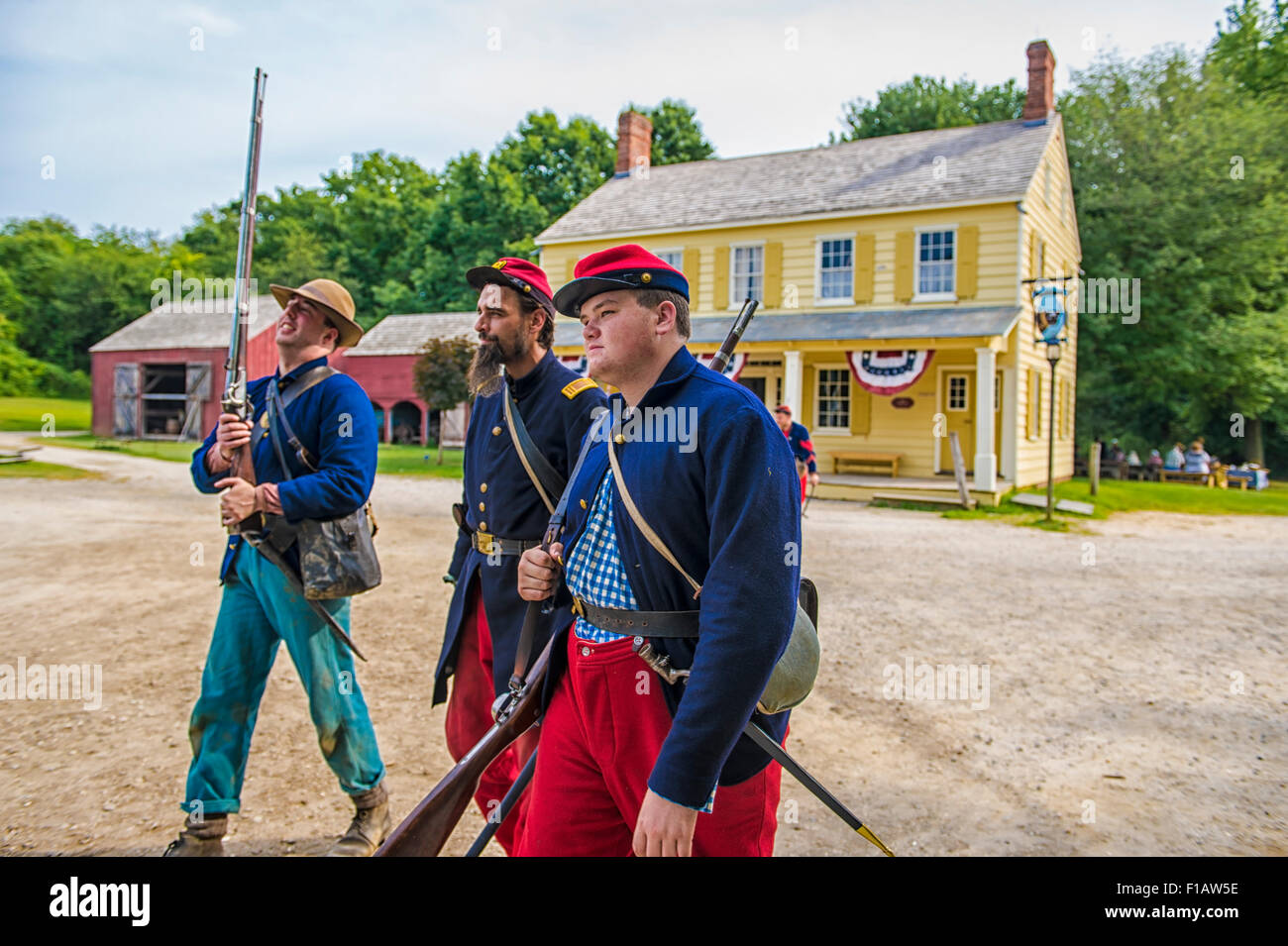 Old Bethpage, New York, USA. 30th August, 2015. At center, Andrew Preble from Long Beach portrays an American Civil War Captain from the 14th Brooklyn Regiment (14th New York State Militia) AKA The Brooklyn Chasseurs, in front of the yellow and white Noon Inn during the Old Time Music Weekend at the Old Bethpage Village Restoration. During their historical reenactments, members of the non-profit 14th Brooklyn Company E wear reproductions of 'The 'Red Legged Devils' original Union army uniform. Credit:  Ann E Parry/Alamy Live News Stock Photo