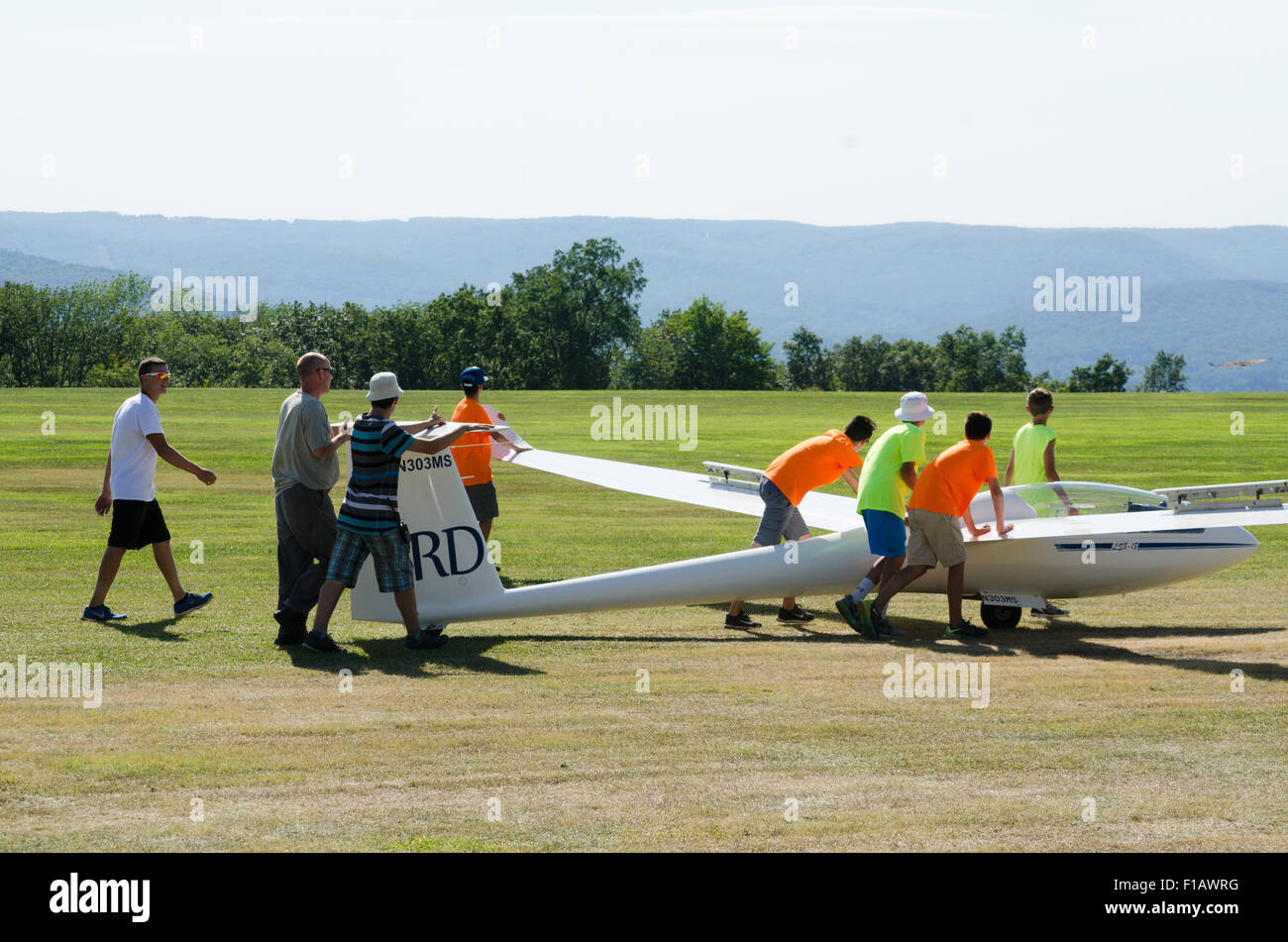 teens and pilot move sailplane to side of runway. Stock Photo