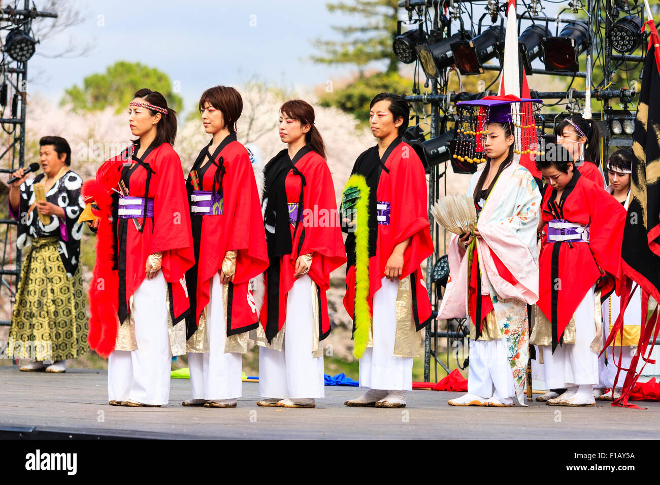Japanese Yosakoi dance festival. Row of dancers wearing red cloaks with Princess in the middle standing on outdoor stage during historical dance. Stock Photo