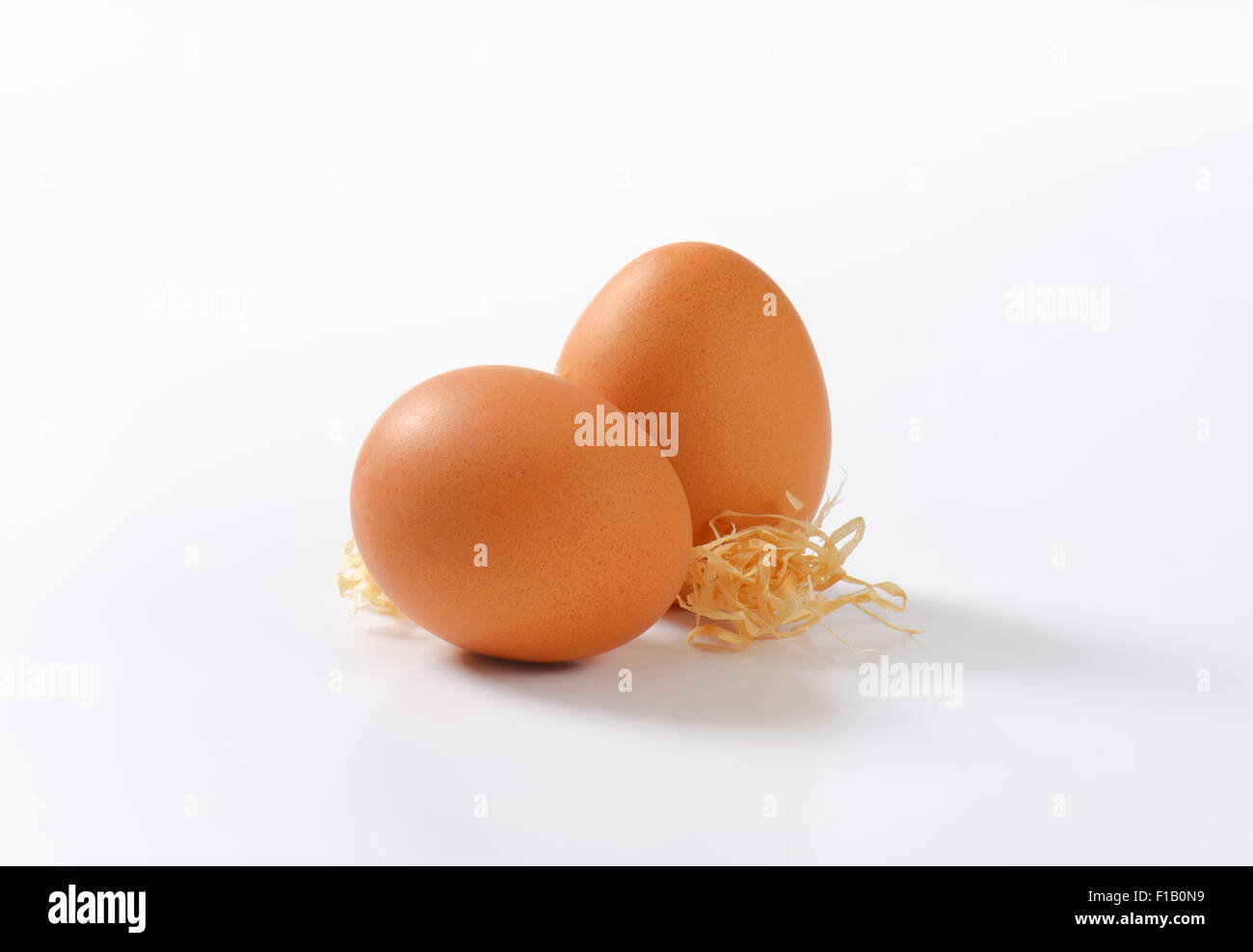 two organic eggs with straw on white background Stock Photo - Alamy
