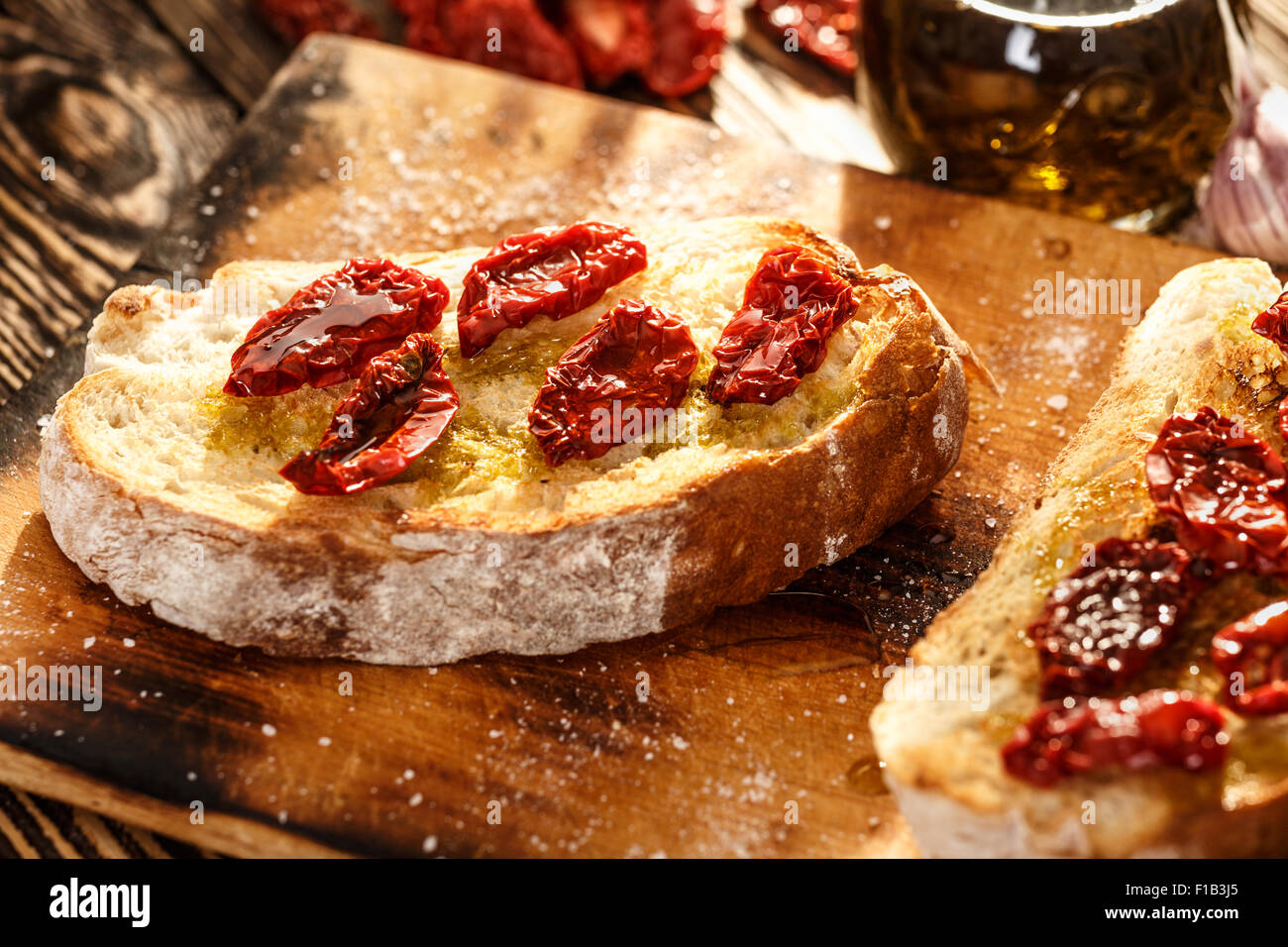 Bruschetta with dried tomatoes, garlic and olive oil. Traditional Italian cuisine sandwich made of grilled ciabatta. Antipasti Stock Photo