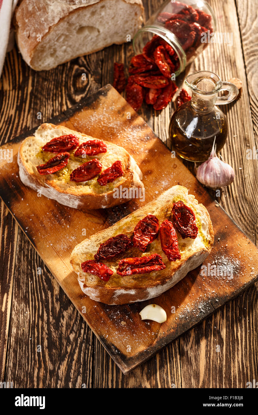 Bruschetta with dried tomatoes, garlic and olive oil. Traditional Italian cuisine sandwich made of grilled ciabatta. Antipasti Stock Photo