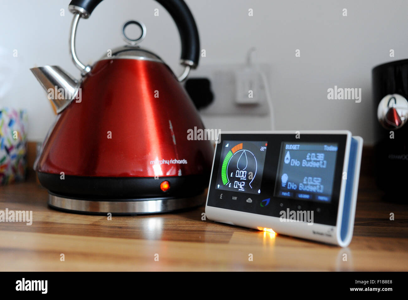 British Gas smart meter showing consumption of electricity and gas used with domestic appliance a kettle in the kitchen Stock Photo