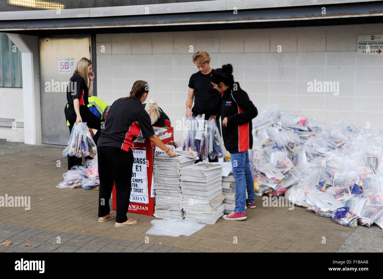 Promotion staff from east Anglian daily Times and Ipswich Star with copies of newspaper Goody bags at football match Suffolk UK Stock Photo