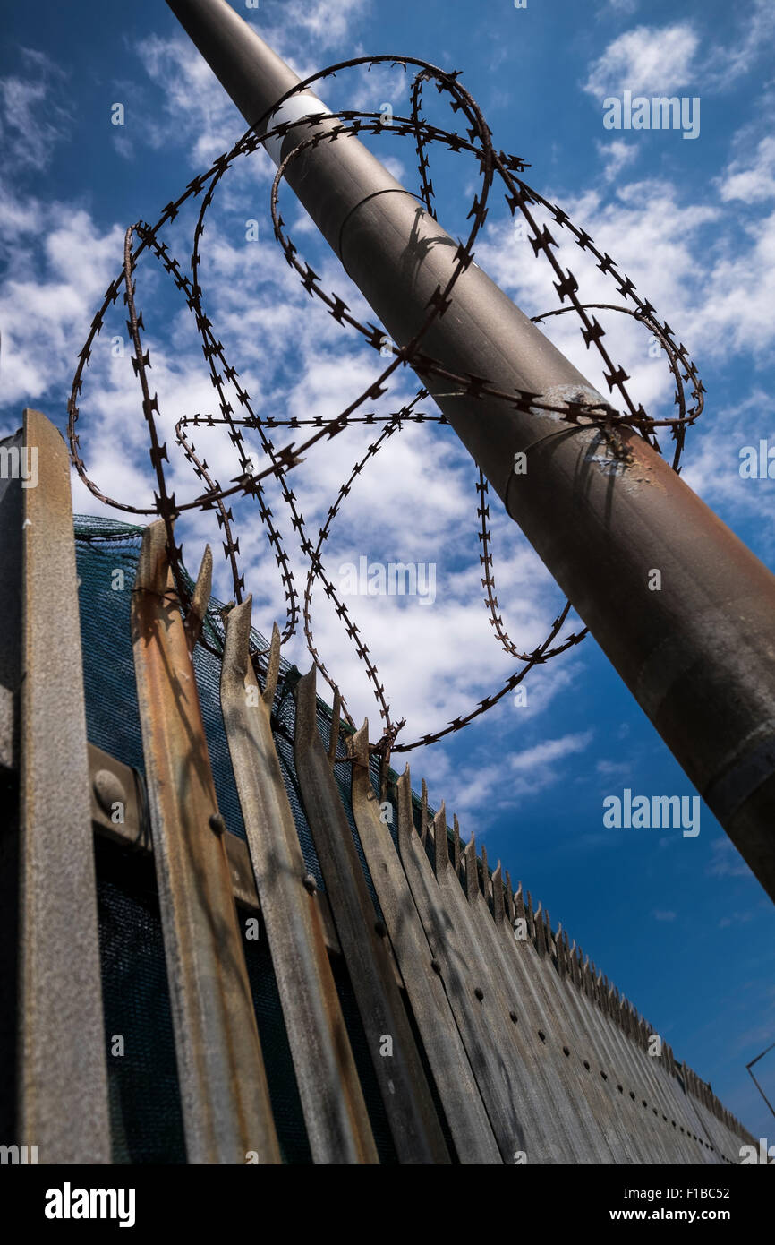 Barbed razor wire wrapped around a lampost by a spiked fence to keep people from climbing in to the Poolbeg generating station i Stock Photo