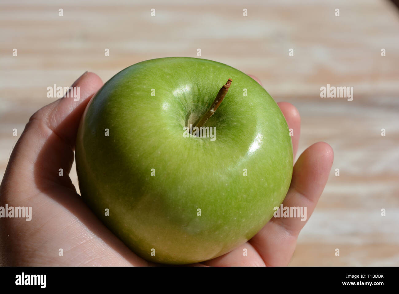 Granny Smith apple held in the hand. Apple for The Teacher. Stock Photo
