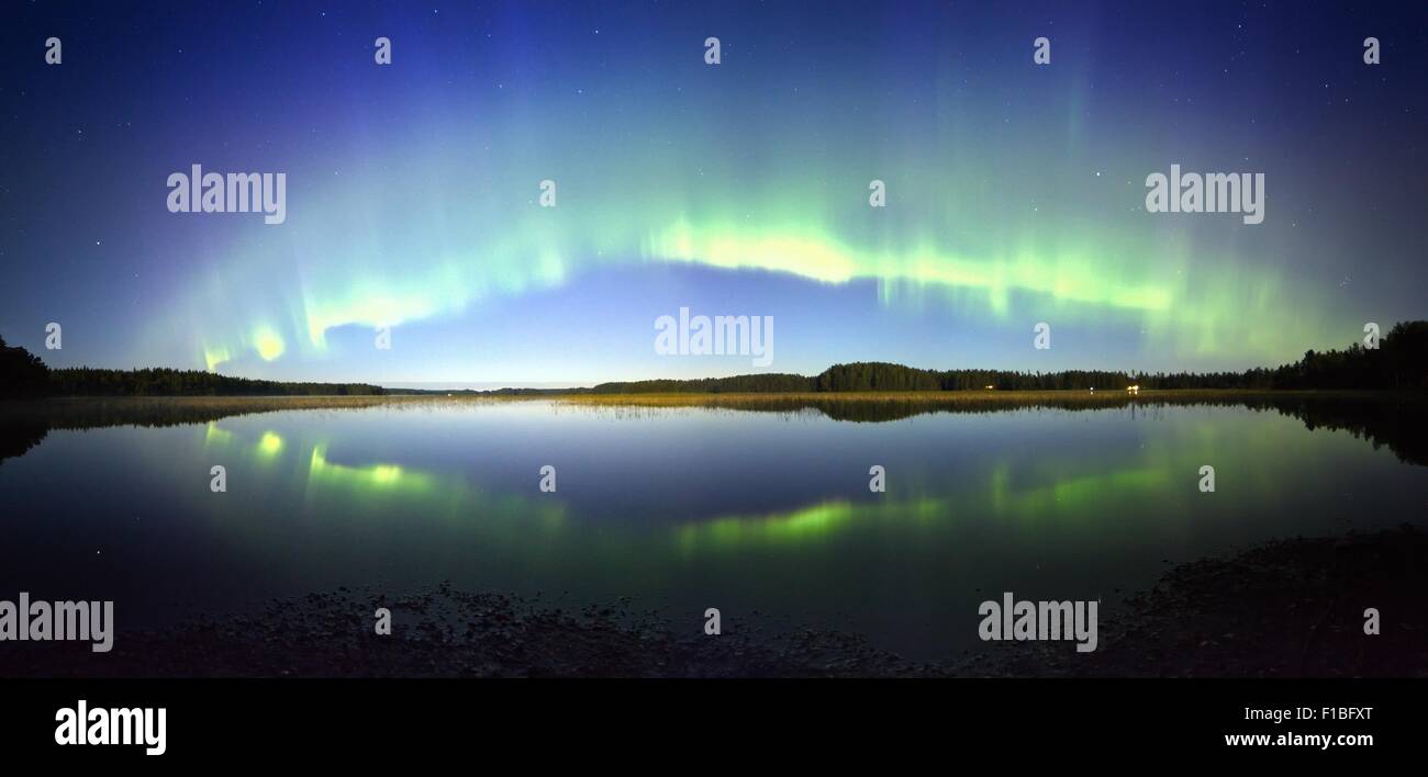 Northern lights panorama with reflection on the lake at night. Stock Photo