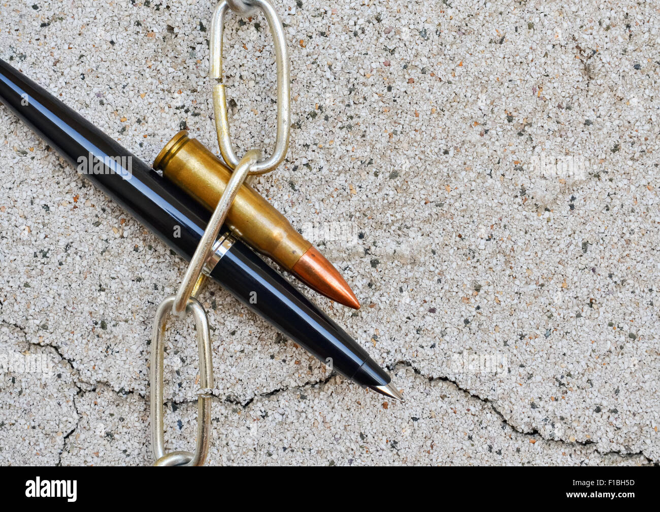 Pen chain and bullet symbolically reflect the interests of the world Stock Photo