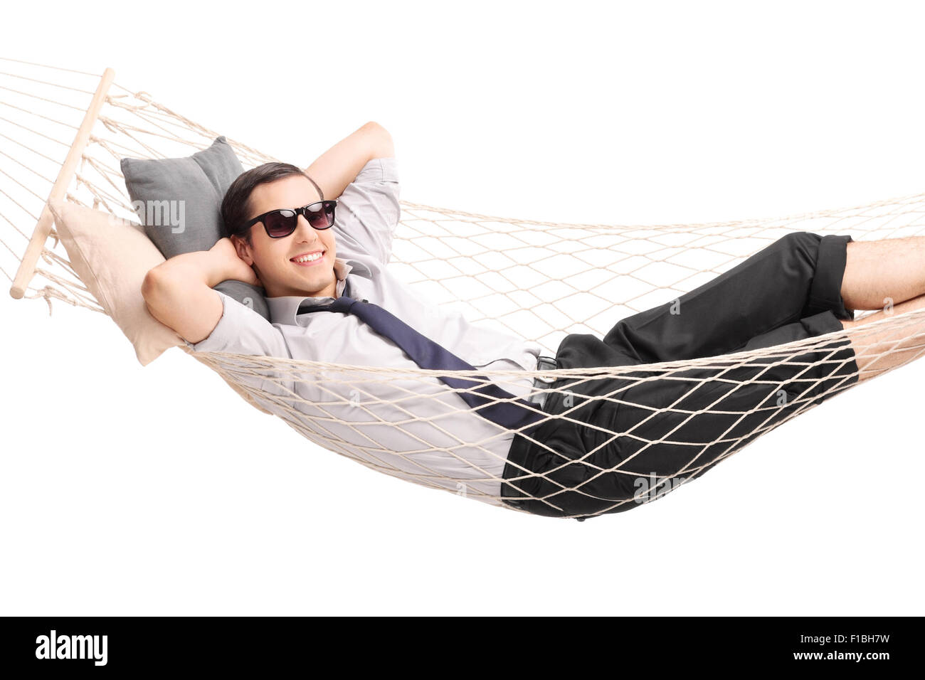 Carefree young businessman lying in a hammock and looking at the camera isolated on white background Stock Photo