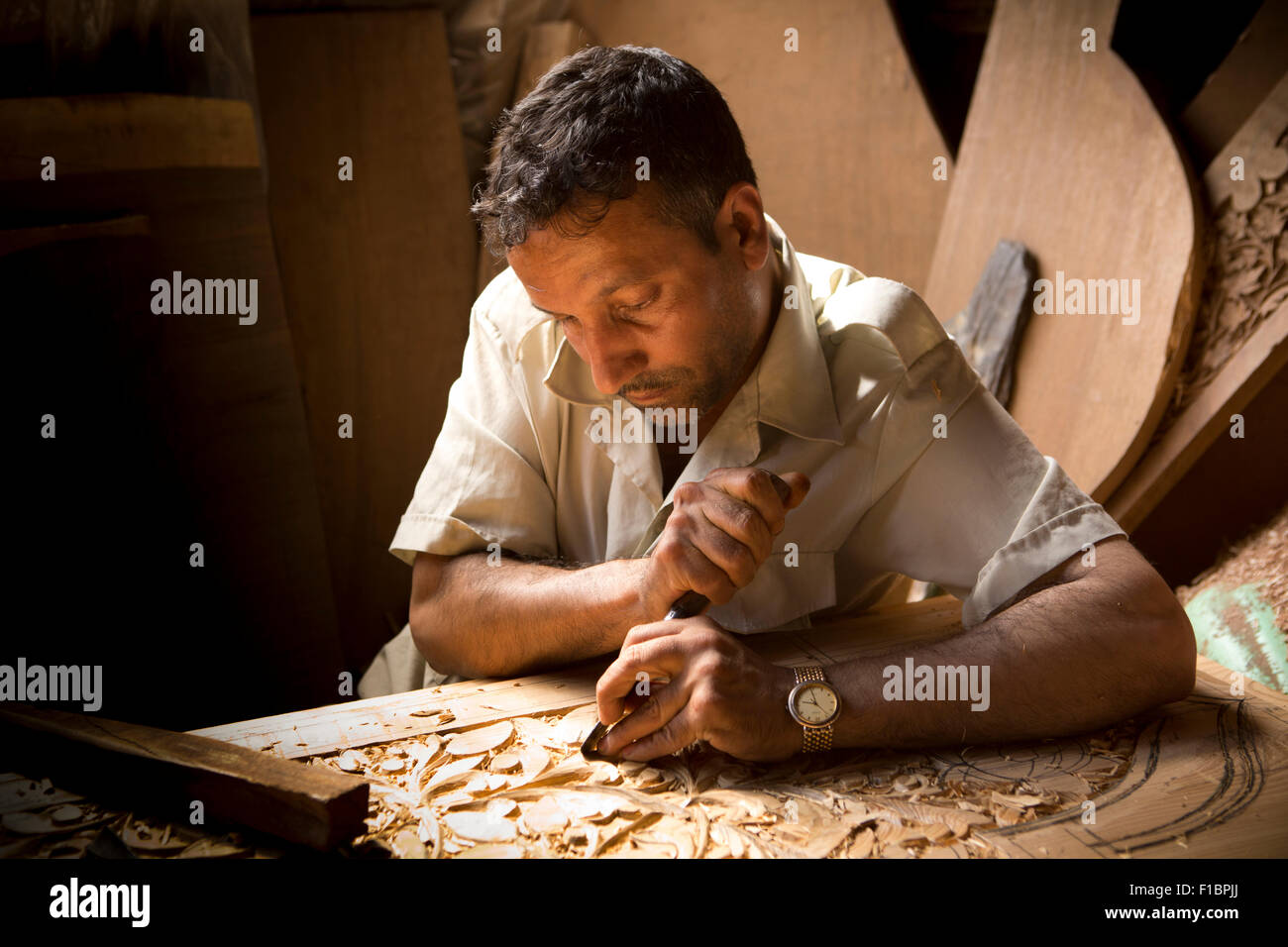 India, Jammu & Kashmir, Srinagar, Old City, crafts, woodcarver carving traditional organic pattern into walnut panel Stock Photo